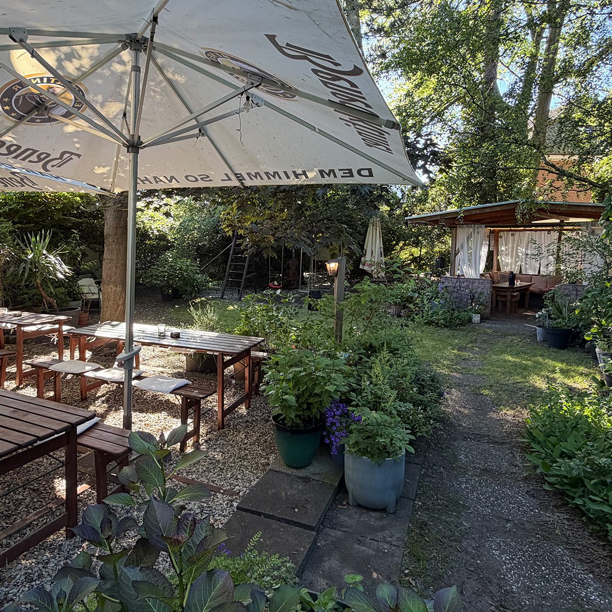 Terrasse im Garten Terrasse im Garten mit Bierzeltgarnituren, große Sonnenschirme, Blumen und Pflanzen